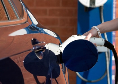 Person putting charging plug into electric vehicle