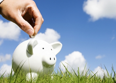 Photo of hand putting coin in piggy bank