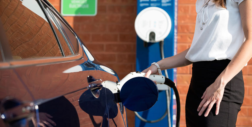 Person connecting electric vehicle charger to car