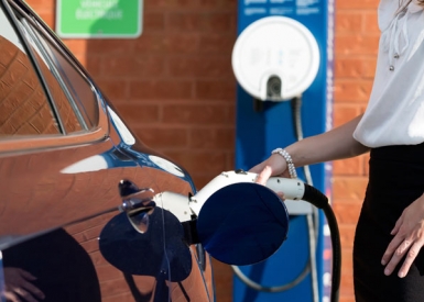 Person connecting electric vehicle charger to car